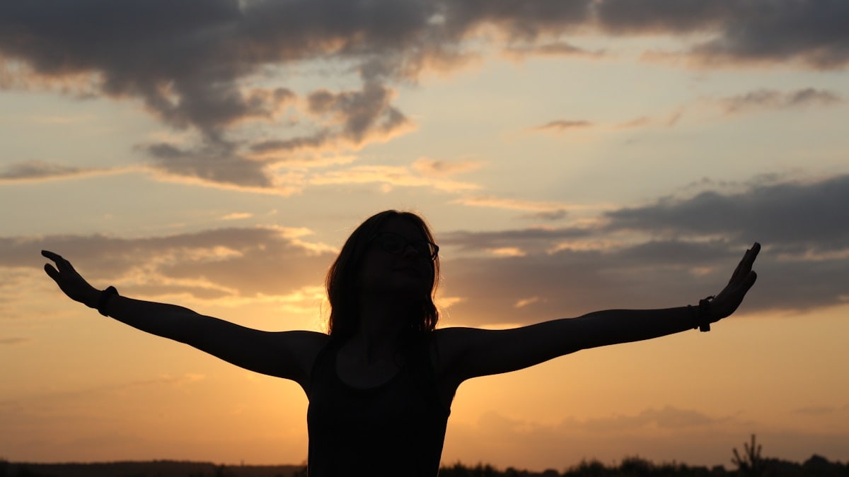 A person standing in a field with their arms outstretched